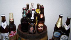 Mehrere Bier-Flaschen stehen aufgereiht auf einer Bar