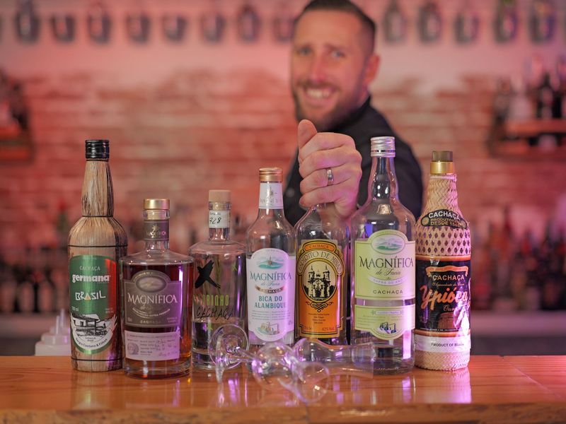 Ein Mann hält eine Flasche Cachaca und lächelt