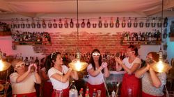 Teilnehmerinnen eines Junggesellinnenabschieds stehen hinter der Bar und schütteln Cocktails