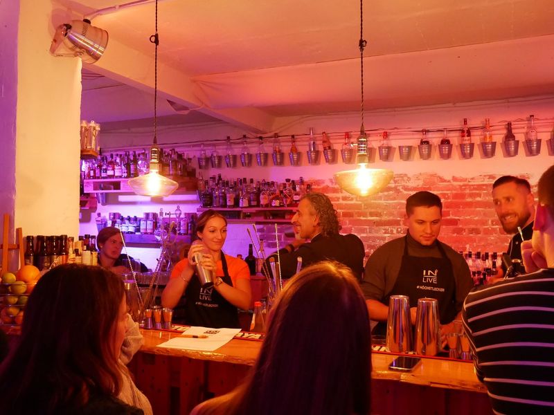 Das Team der Cocktailschule steht hinter der Bar und mixt Cocktails