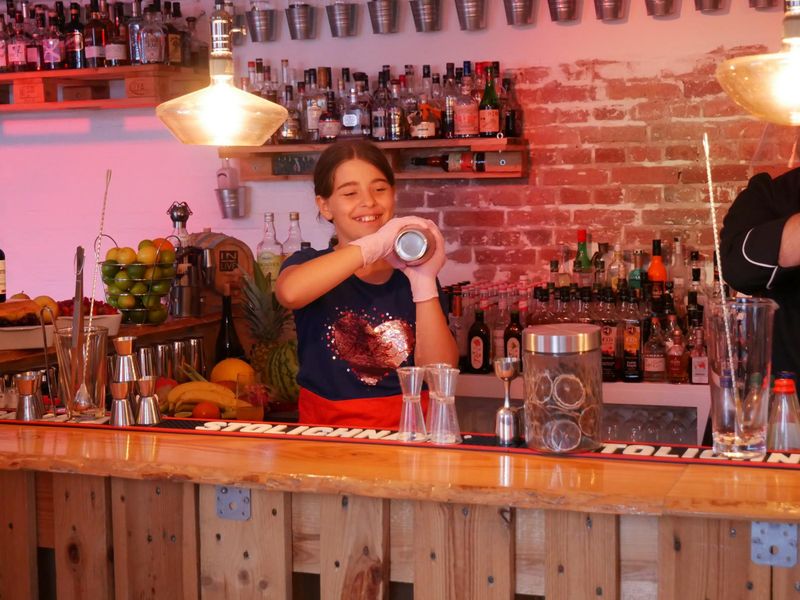 Teilnehmer bei dem Kindergeburtstags-Cocktailworkshop mixen hinter der Bar Cocktails