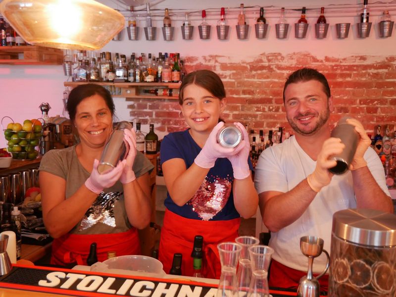 Teilnehmer bei dem Family Cocktailworkshop mixen hinter der Bar Cocktails