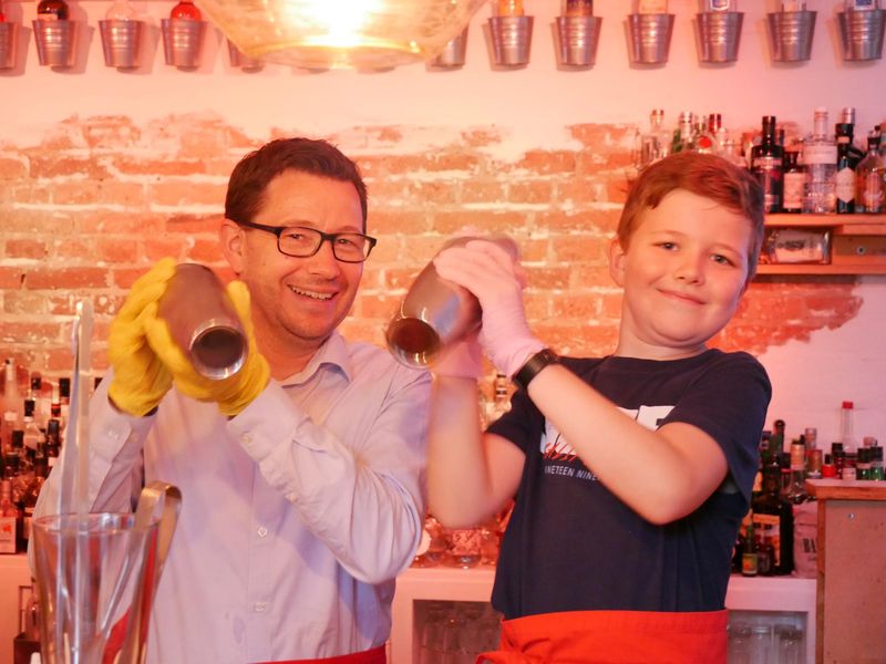 Teilnehmer bei dem Kindergeburtstags-Cocktailworkshop mixen hinter der Bar Cocktails