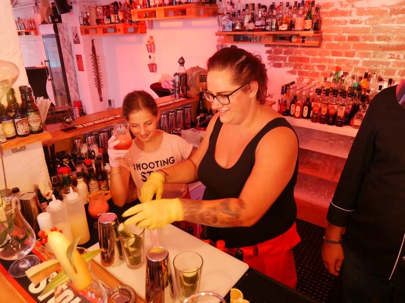 Teilnehmer bei dem Family Cocktailworkshop mixen hinter der Bar Cocktails