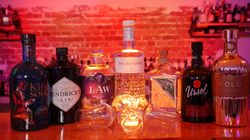 Mehrere Gin-Flaschen stehen aufgereiht auf einer Bar