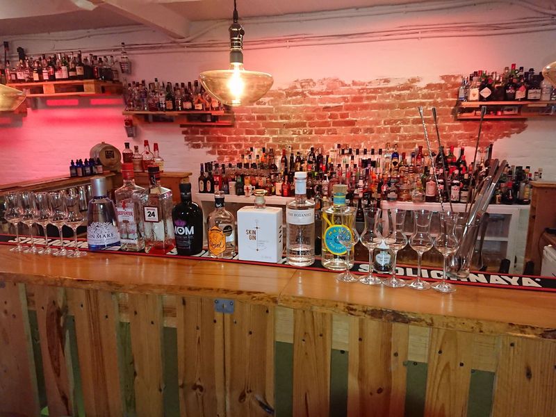 Mehrere Gin-Flaschen stehen aufgereiht auf einer Bar