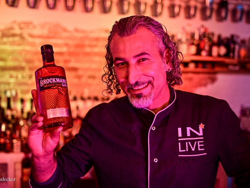 Ein Mann hält eine Flasche Gin und lächelt