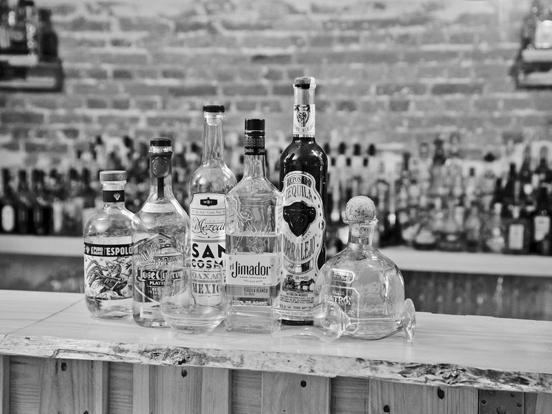 Mehrere Tequila-Flaschen stehen aufgereiht auf einer Bar